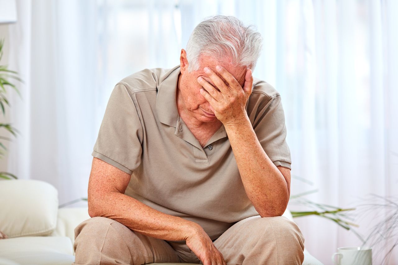 Tired older man with palm on face.