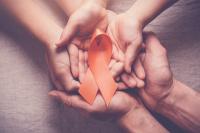 Orange multiple sclerosis awareness ribbon cupped in hands | Image credit: SewcreamStudio - stock.adobe.com