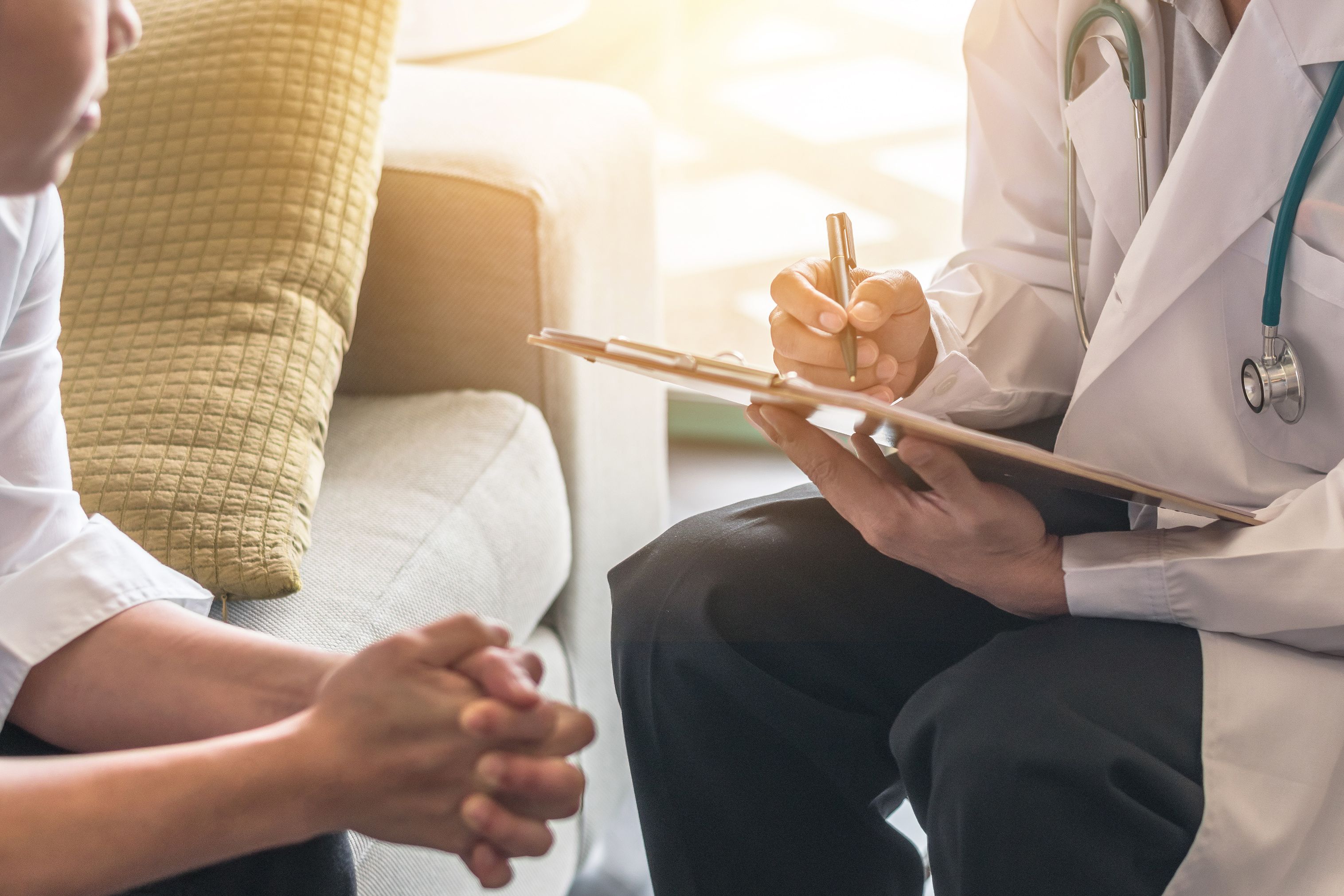 patient talking to a doctor while the doctor takes notes on a clipboard