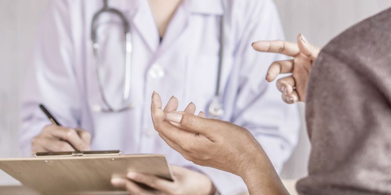 Physician with a clipboard speaking to patient.