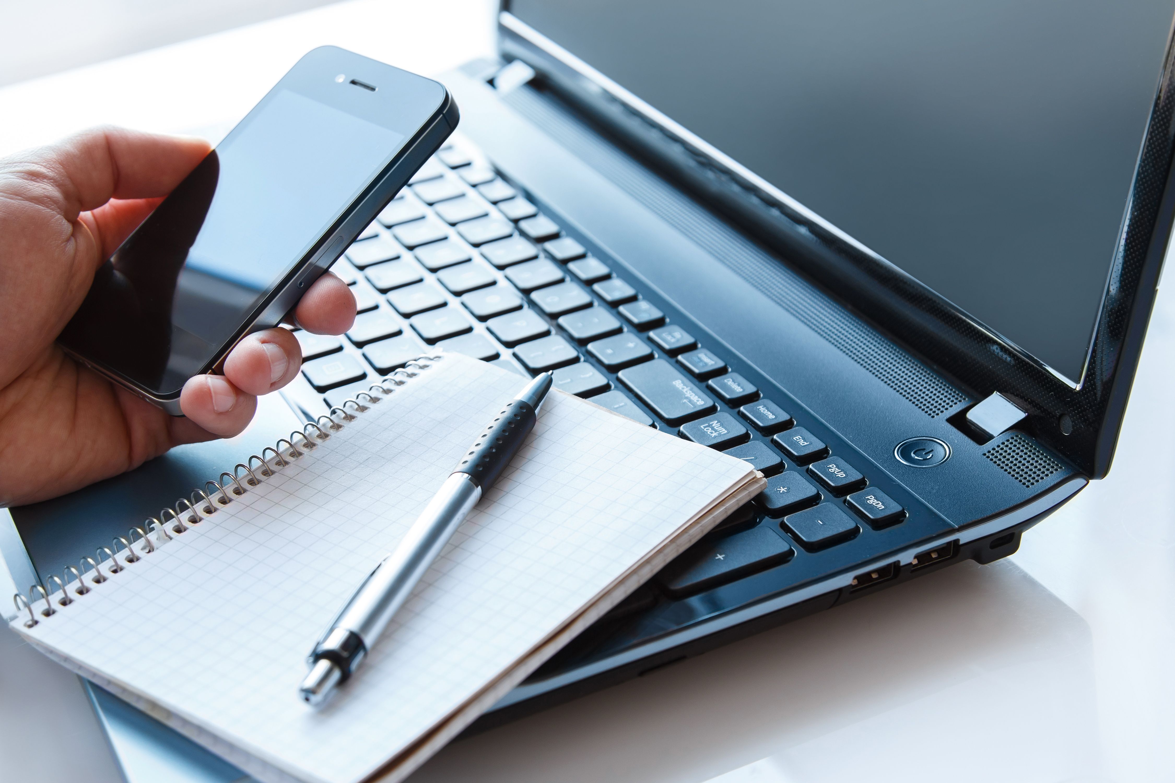 laptop, cell phone, and notebook and pen