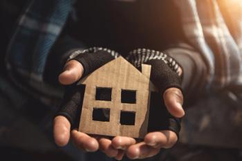 Hands of a person experiencing homelessness holding a cardboard house | Image Credit: 2B - stock.adobe.com