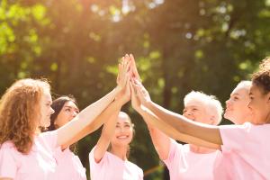 Group of diverse women with pink shirts high-fiving in a circle | Image Credit @Prostock-studio-adobestock_.jpeg