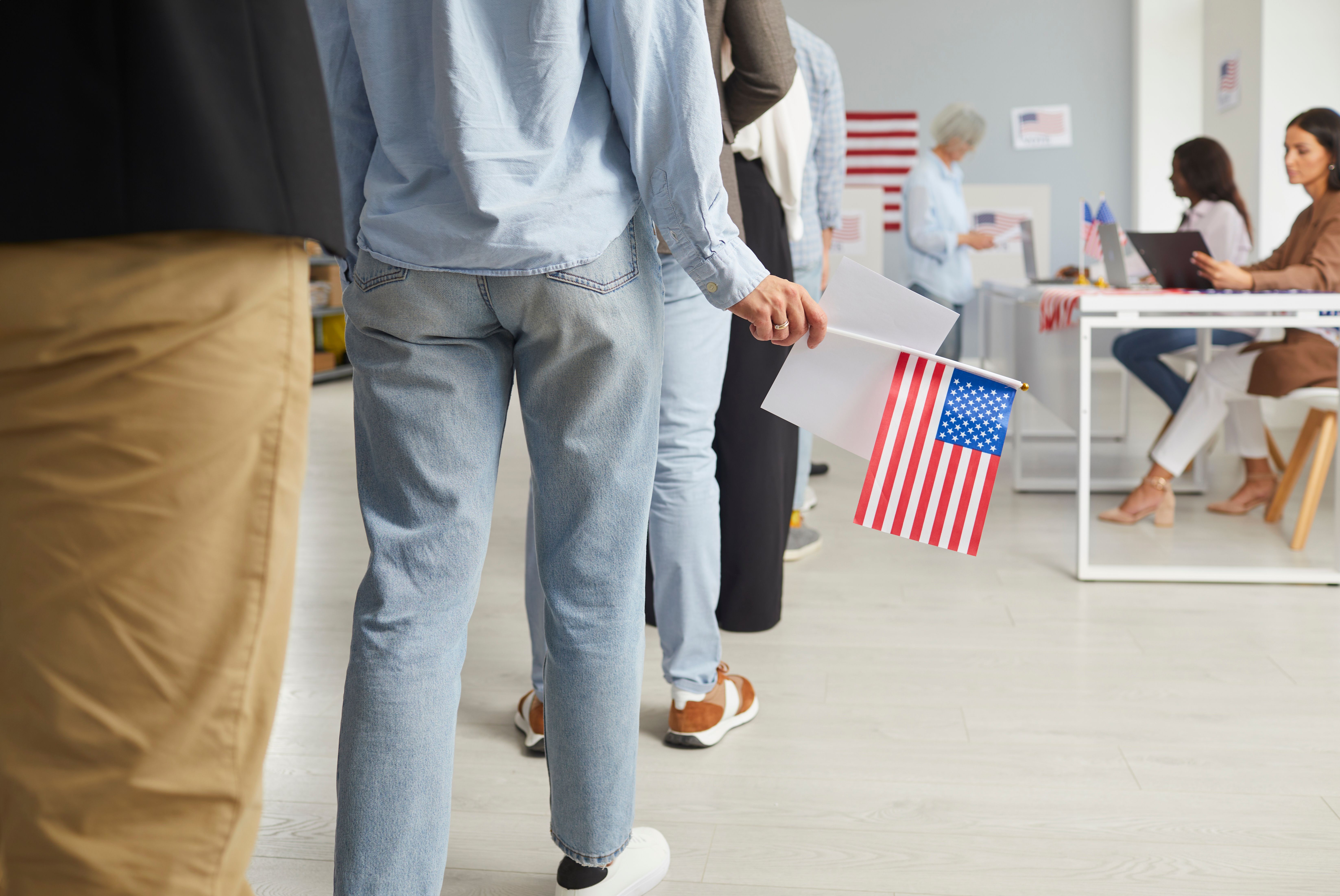 Cropped photo of a group of unrecognizable american citizens people standing in polling station. Voters standing in a queue at vote center getting ballot paper. Election day - Studio Romantic - stock.adobe.com