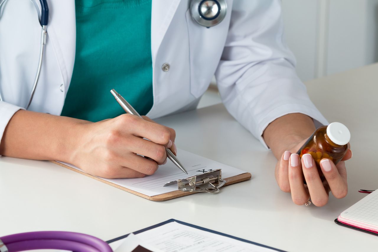 Physician evaluating pill bottle. 