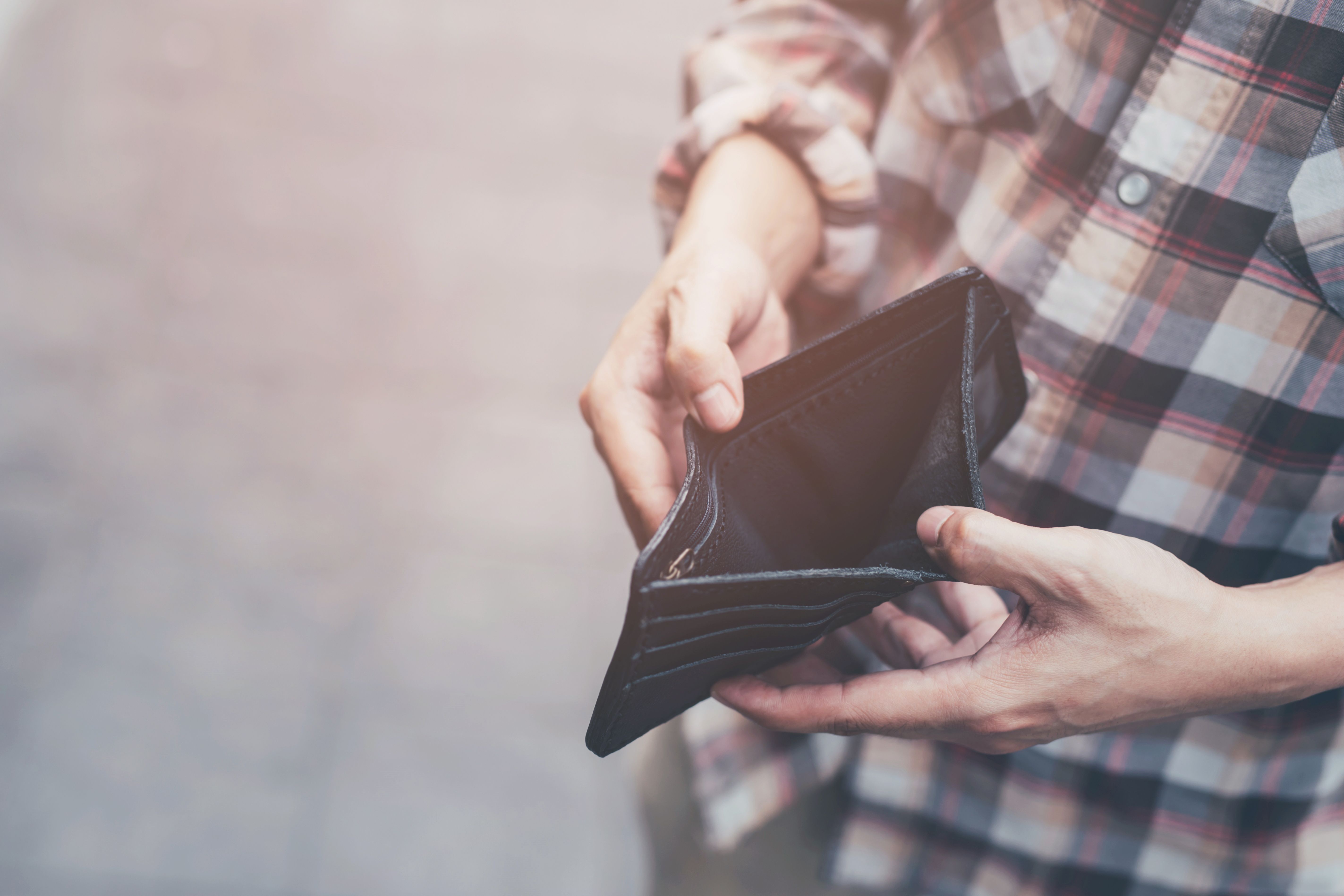 Man holding an empty wallet | Image Credit: methaphum - stock.adobe.com