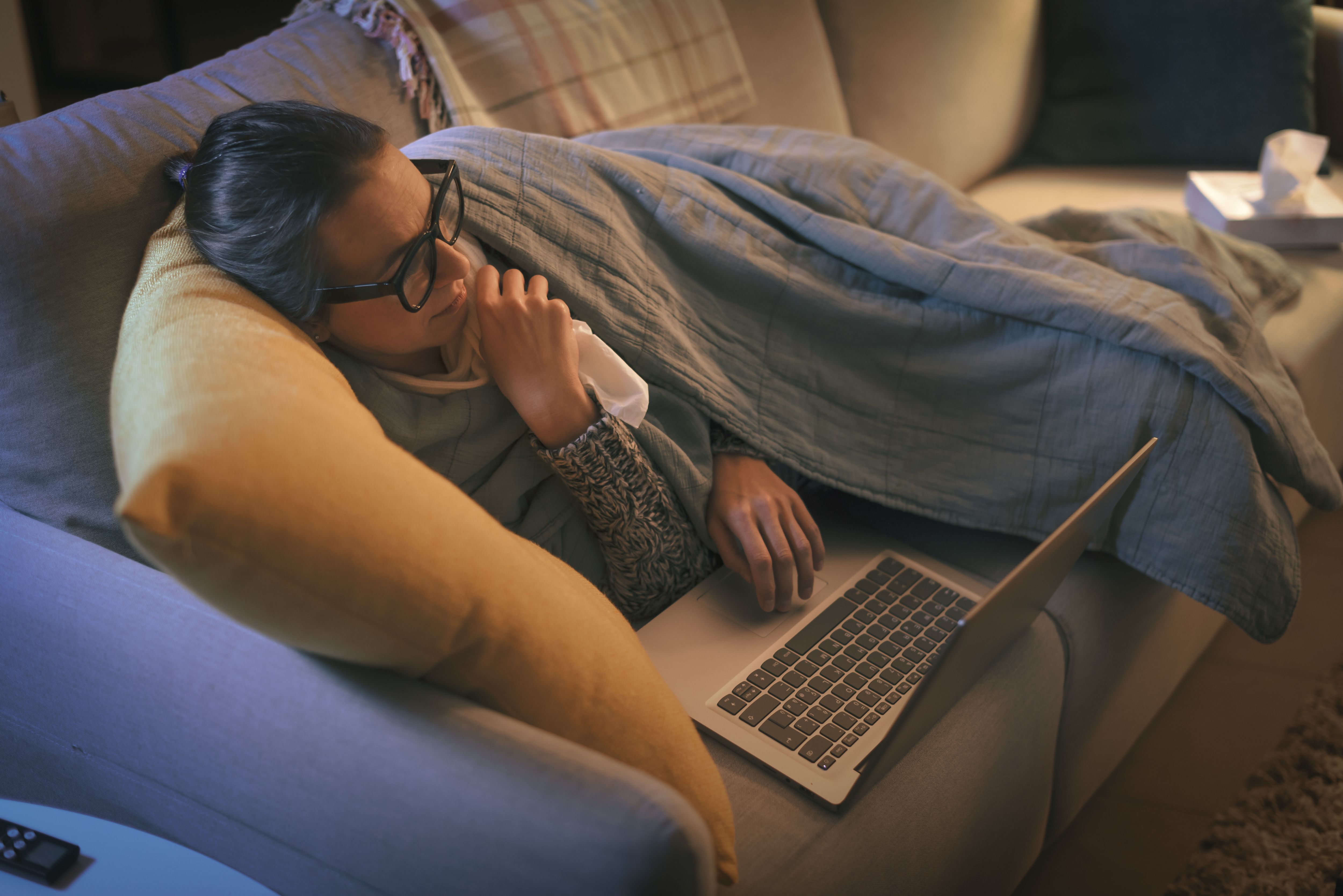 Sick woman with flu connecting with her laptop - StockPhotoPro - stock.adobe.com