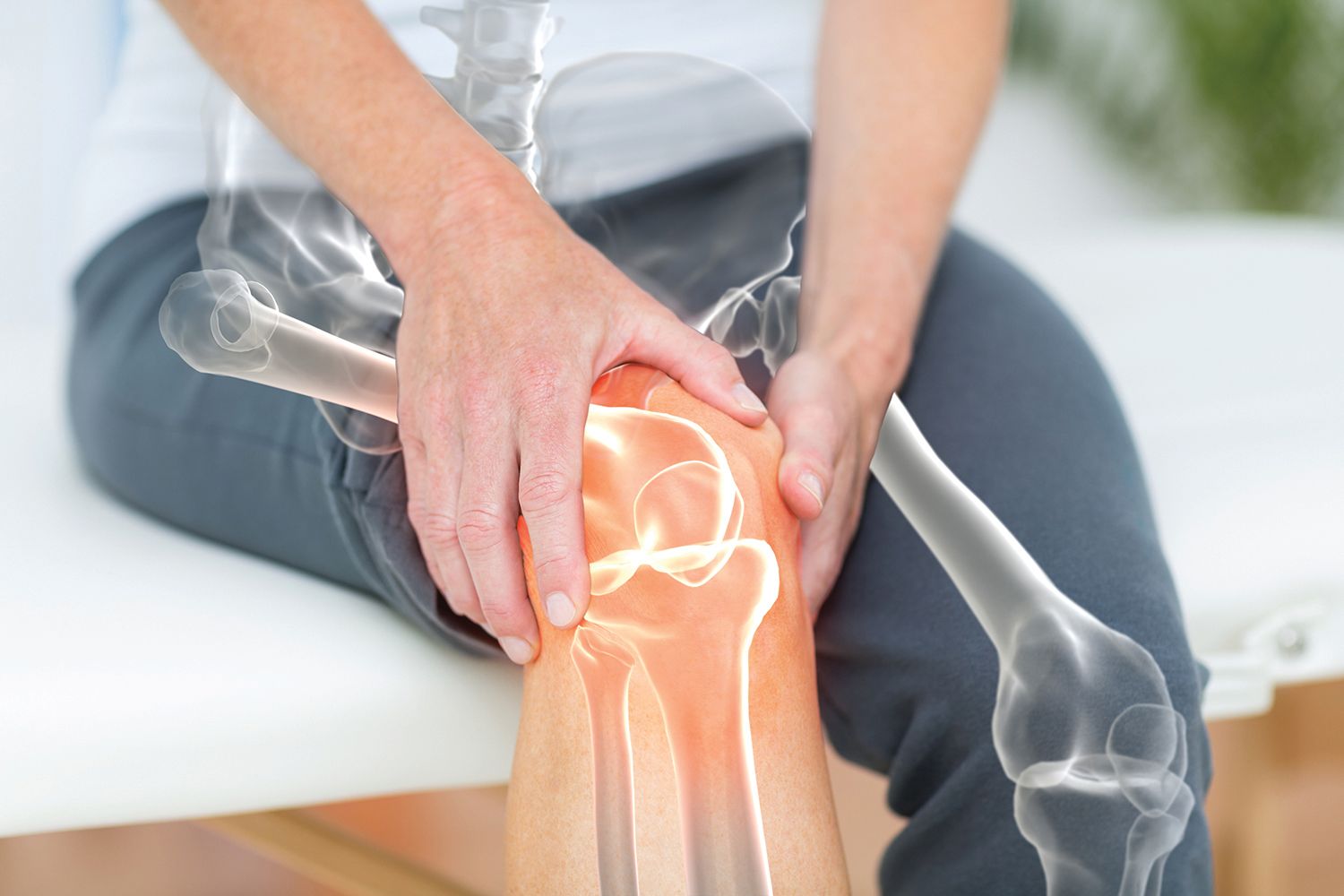 man holding his knee, which shows an xray image of his bones