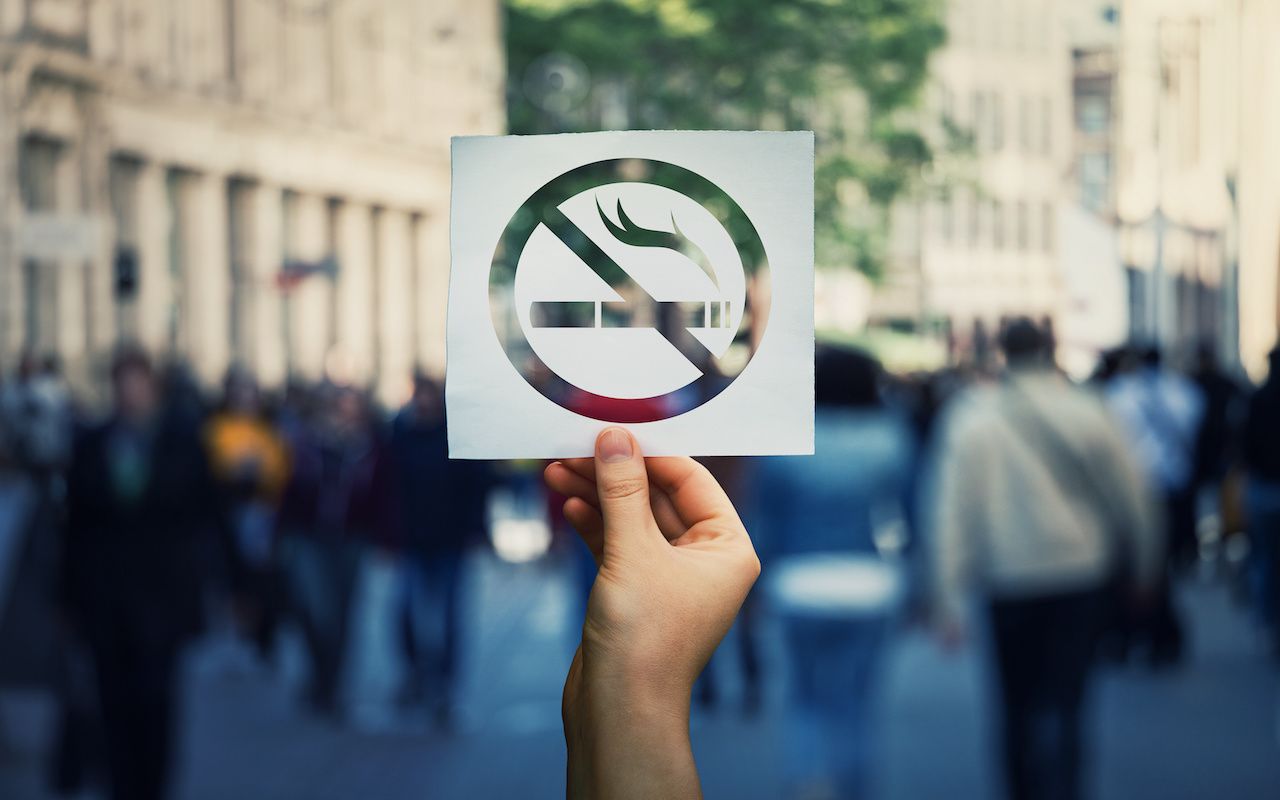 person holding a "no smoking" sign