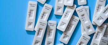 Mass testing for Covid-19 / SARS-CoV-2 infection concept: Several rapid antigen test kits. One kit in the middle showing a positive result (two lines visible) | Image Credit: Andreas Prott - stock.adobe.com