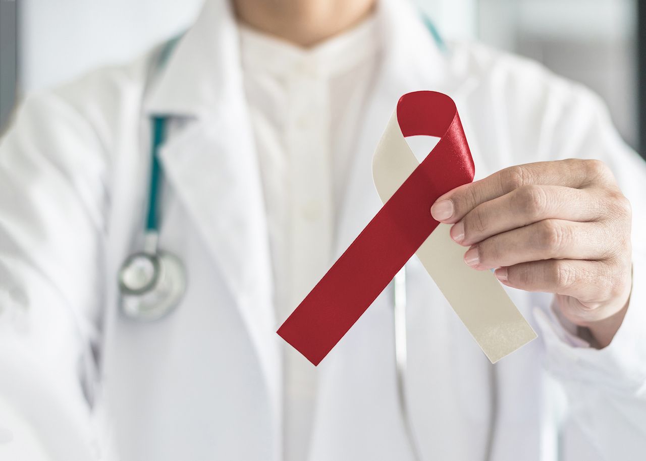 Doctor holding a burgundy and white head and neck cancer ribbon | Image credit: Chinnapong - stock.adobe.com