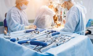 Surgical tools in foreground with surgeons performing an operation in the background | Image credit: romaset - stock.adobe.com
