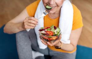 Older woman eating salad on yoga mat | Image credit: Prostock-studio – stock.adobe.com