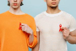 2 men holding 2 red ribbons. | Image credit: @ViDiStudio_AdobeStock.jpeg