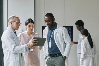 Group of doctors talking and looking at tablet | Image credit: Seventyfour – stock.adobe.com