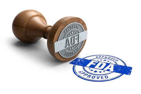 Stamp that says "FDA Approved" in blue ink. | Image Credit: Surendra - stock.adobe.com