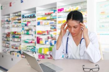 Stressed pharmacist in dispensing room | Image credit: Boonterm – stock.adobe.com