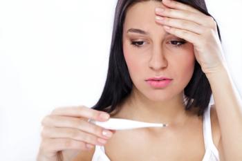 woman with fever looking at thermometer