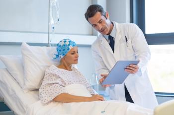 Woman with cancer in hospital bed speaking with her male doctor about treatment | Image Credit: Rido - stock.adobe.com