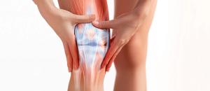 Image of partially exposed knee that is inflamed with persons hands rubbing it due to pain.| Image Credit: BigBlueStudio - stock.adobe.com