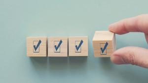 Hand holding wooden block with tick mark, satisfaction survey ,mental health assessment, checklist business, project tracking, goal tracker, task completion concept. Image Credit: ©sewcream - sewcream-stock.adobe.com