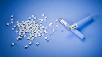 Injection pens lying next to white oral tablets on a blue surface. | Image Credit: © Andreas Prott - stock.adobe.com