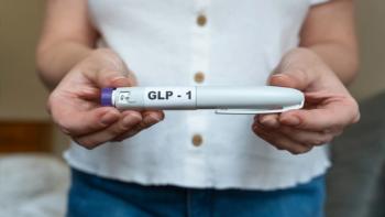 Photograph of a woman holding a GLP-1 injection pen in front of her abdomen. | Image Credit: © Kateryna - stock.adobe.com