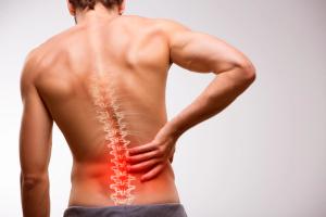 Illustration of a man experiencing lower back pain, with the spine highlighted. | Image Credit: © BigBlueStudio - stock.adobe.com