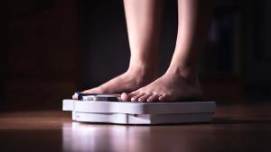 Feet on scale. Weight loss and diet concept. Woman weighing herself. Fitness lady dieting. Weightloss and dietetics. Dark late night mood. | Image credit: © terovesalainen - © terovesalainen - stock.adobe.com