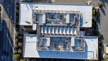 Aerial top down view of a flat roof of a commercial building with industrial HVAC units. Ponding dirty water spots. | Image Credit: © MichaelVi - Stock.adobe.com