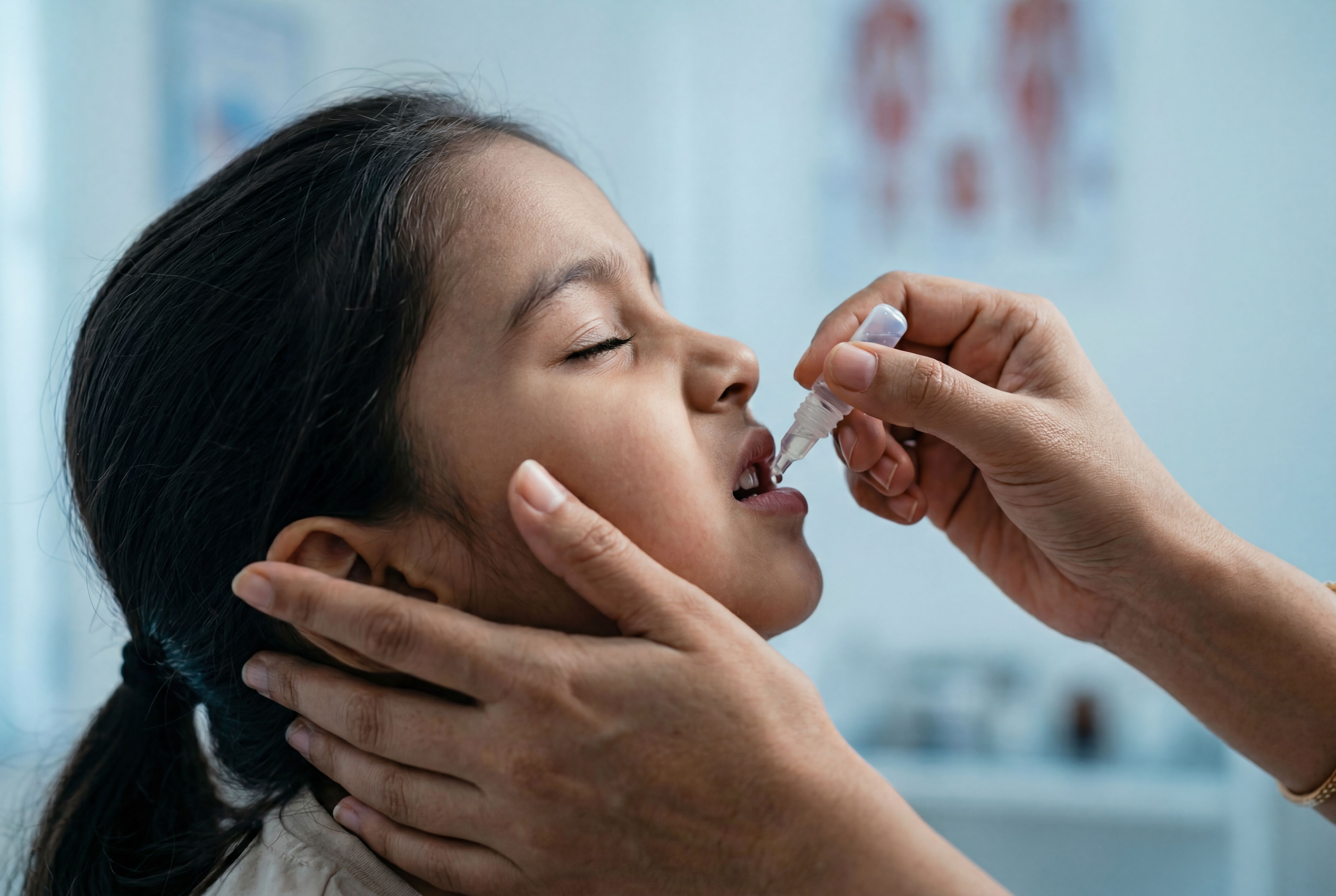 Young child receiving oral vaccine from a healthcare worker representing Shigella disease prevention in pediatric global health. | Image Credit: © Meow Creations -stock.adobe.com.
