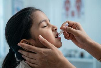 Young child receiving oral vaccine from a healthcare worker representing Shigella disease prevention in pediatric global health. | Image Credit: © Meow Creations -stock.adobe.com. 