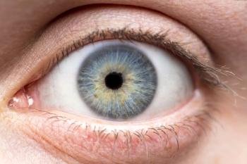 Close-up photograph of a wide-open human eye with a blue-gray iris flecked with gold, a dark pupil, and visible upper and lower eyelashes. | Image Credit: © bradleyblackburn - stock.adobe.com