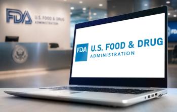 A laptop displaying the FDA logo, with FDA office signage visible in the background. | Image Credit: © gguy - stock.adobe.com