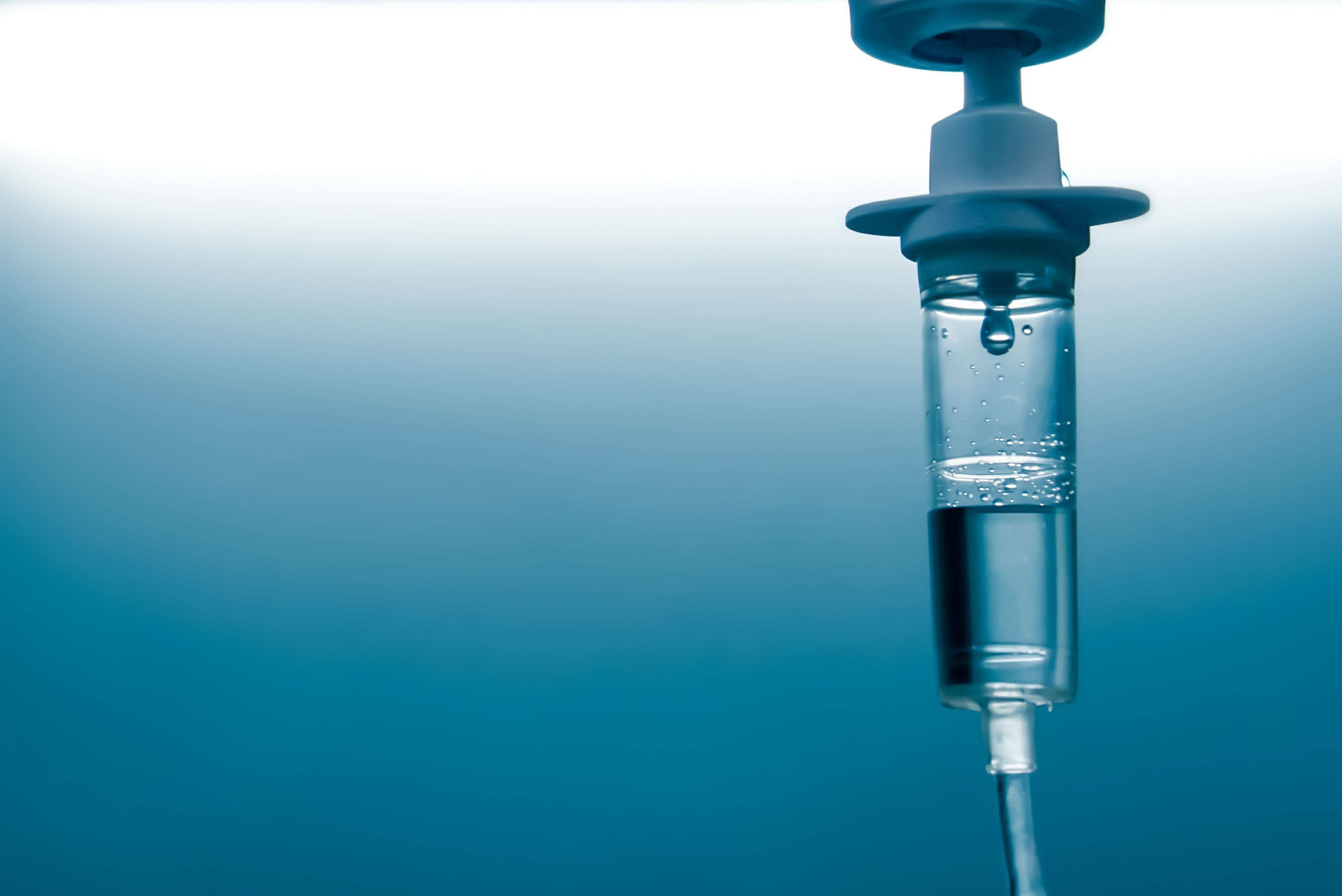 Close-up of an IV drip line with fluid droplet, blue-toned background. | Image Credit: © doucefleur - stock.adobe.com