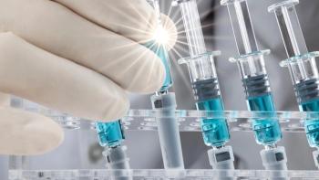 Closed up image of a doctor holding a glass syringe with several other syringes prefilled with blue liquid on a rack. Covid-19 vaccination concepts. | Image credit: © SOPONE - © SOPONE - stock.adobe.com 