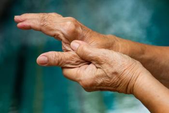 Close-up of an older person's hands, with the thumb of one hand pressing into the palm of the other, against a blurred teal background. | Image Credit: © eyepark - stock.adobe.com