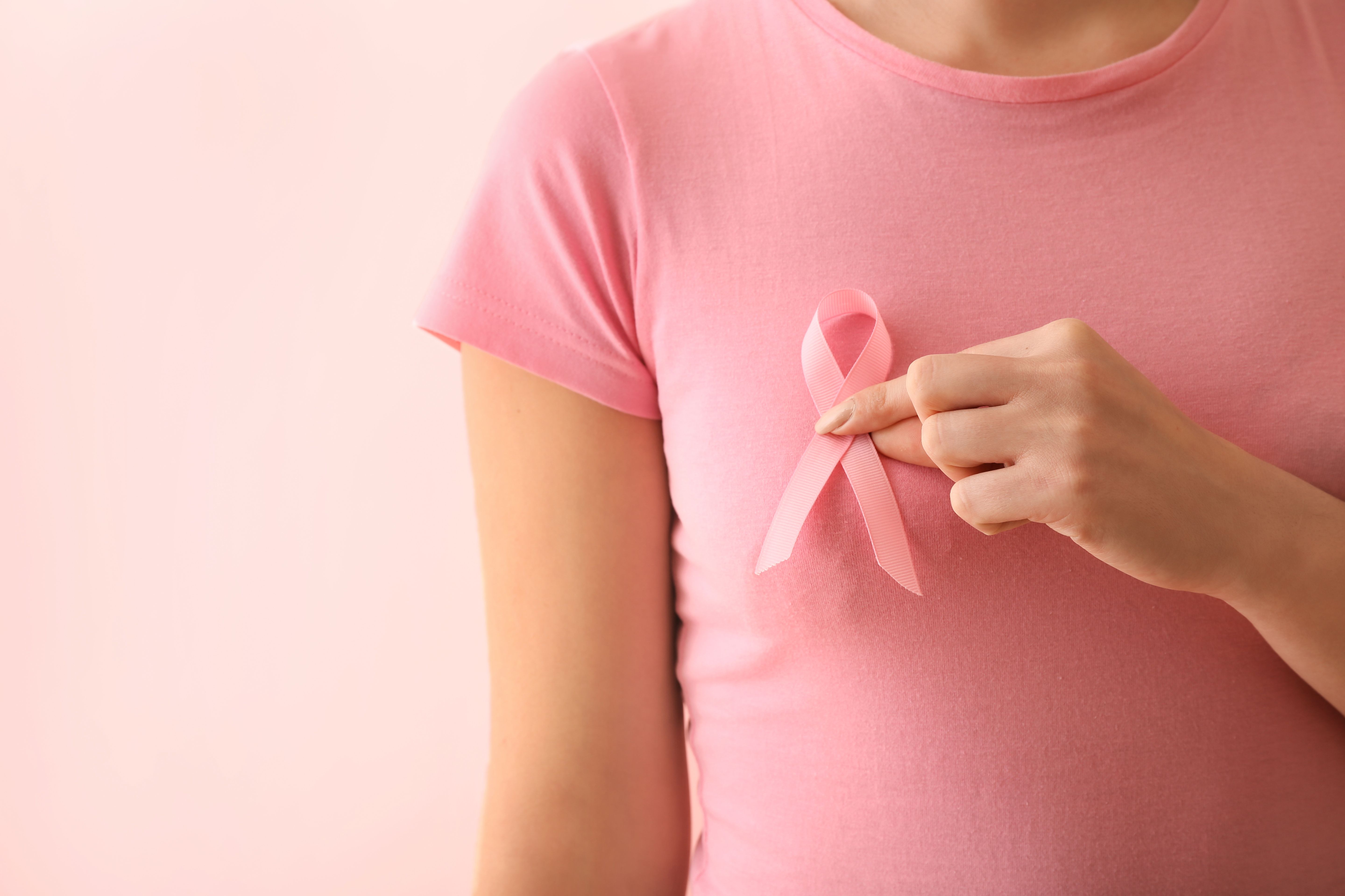 Woman with pink ribbon on color background. Breast cancer awareness concept | Image Credit: © Pixel-Shot - stock.adobe.com