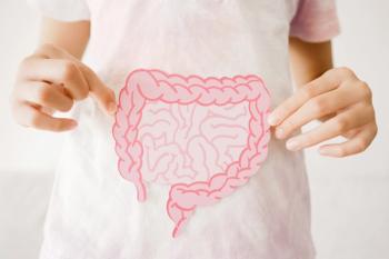 A child in a light pink tie-dye shirt holds a pink paper cutout of the large and small intestines in front of their abdomen. | Image Credit: © SewCreamStudio - stock.adobe.com