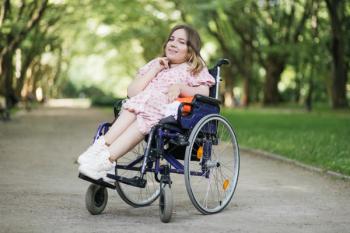 Portrait of pleasant young woman with spinal muscular atrophy smiling on camera among green summer park. Female person who using wheelchair. Concept of people with disability. | Image Credit: ©  sofiko14 - stock.adobe.com