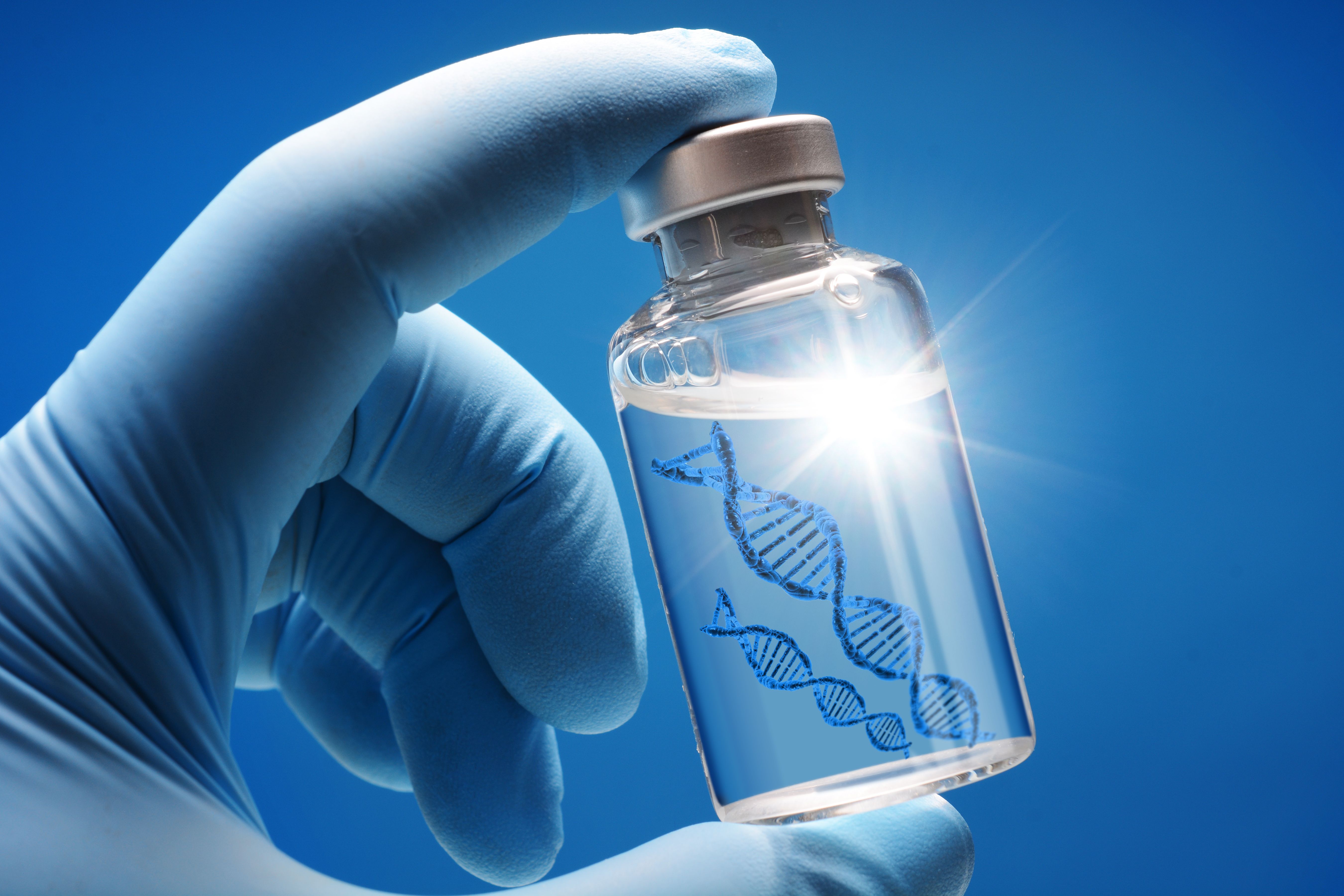Doctor or scientist shows a vial of genetic agent as a vaccine or therapy against Corona or Covid-19 as a symbolic image | Image Credit: © Dan Race - stock.adobe.com