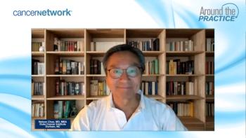 Nelson Chao, MD, smiles for the camera in front of a large wooden bookshelf, wearing glasses and a white button-down shirt.
