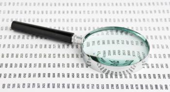 magnifying glass looking at a data spreadsheet