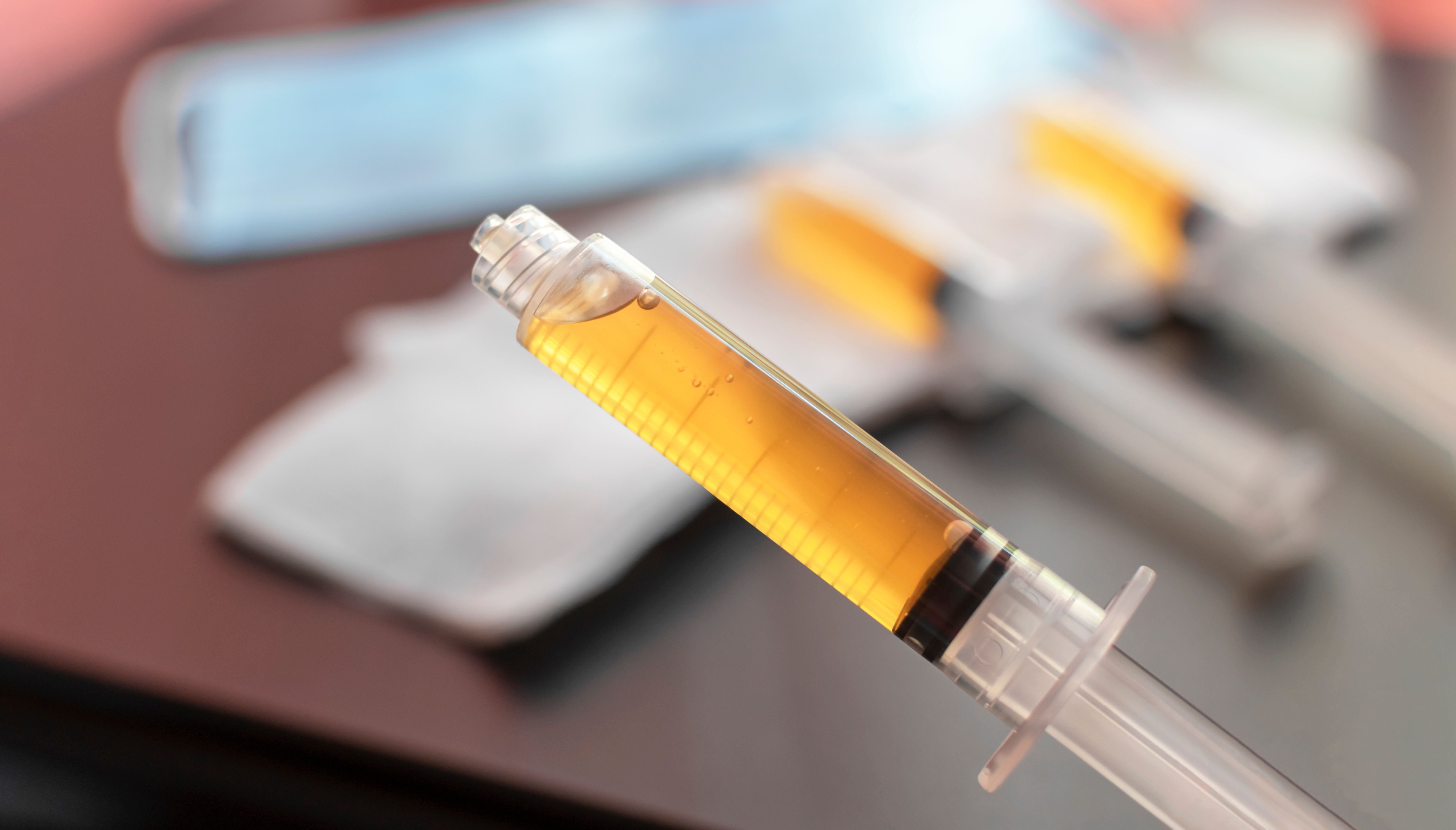 Blood plasma in a syringe on a blurred background. Blood plasma as a solution for the treatment of coronavirus. Platelet-rich plasma preparation for plasmolifting therapy. Selective focus. | Image Credit: © Elena - stock.adobe.com