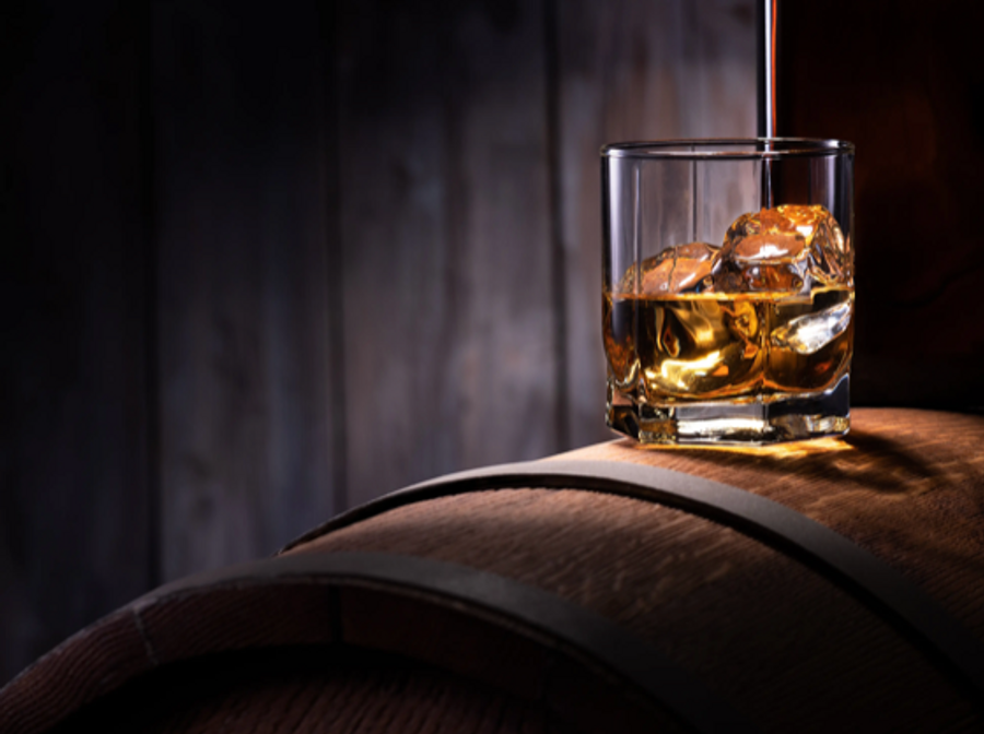 glass of whiskey atop a wooden barrel
