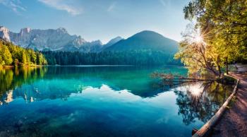 blue lake surrounded by trees. Mountains are in the background.