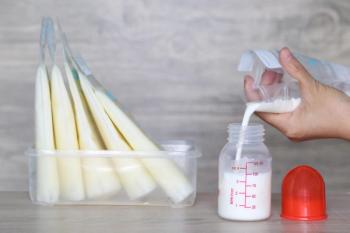 woman pouring milk in to bottles for new baby on wooden table | Image Credit: © Monthira - stock.adobe.com