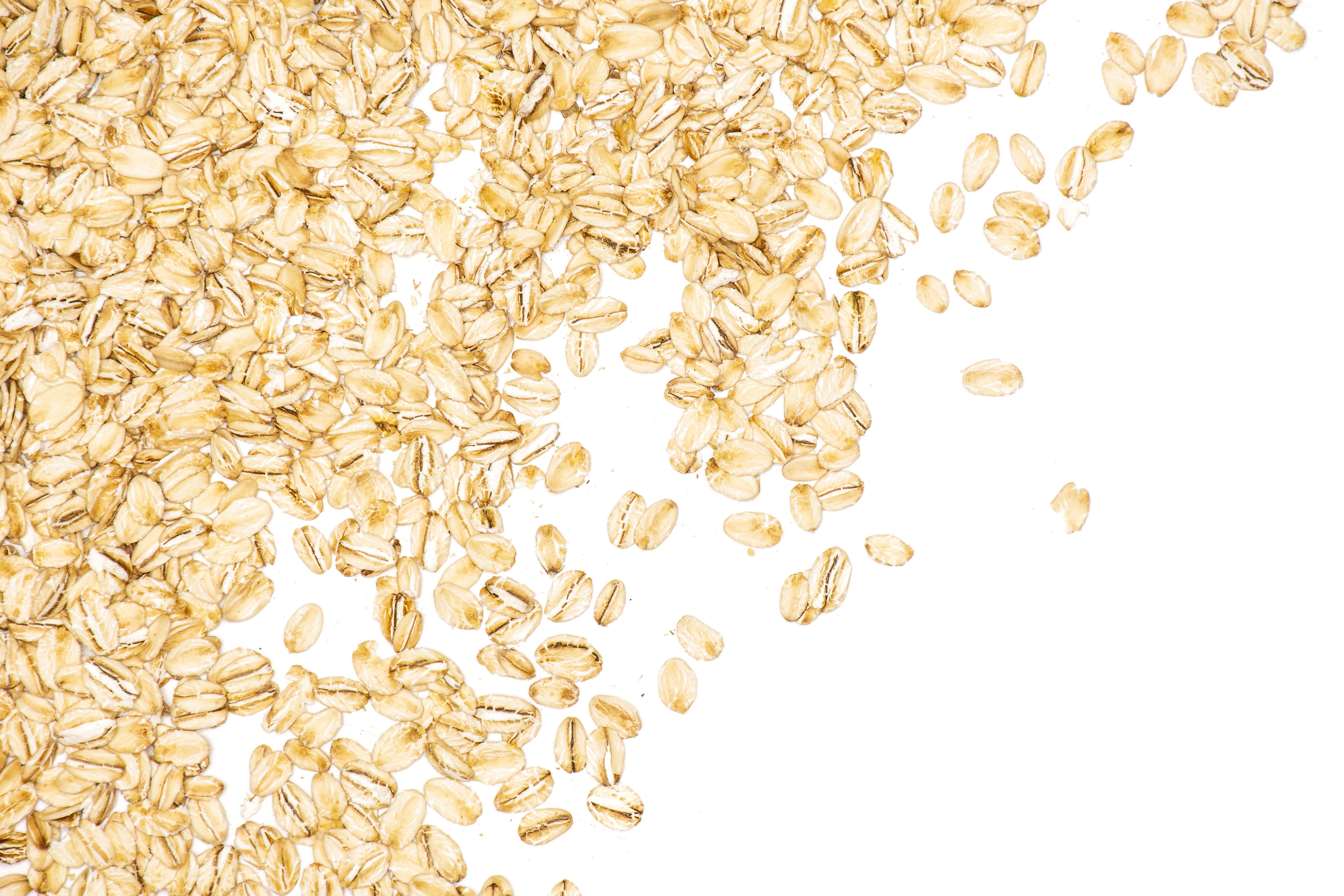 Lot of whole flat raw rolled oats left upper corner isolated on white background | Image Credit: ©PIXbank - stock.adobe.com