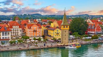 Lindau, Germany. Antique Bavarian town in Bavaria at coastline of Lake Constance (Bodensee). Habour along embankment with traditional houses and tower. Sunset evening landscape. | Image Credit: © Yasonya - stock.adobe.com