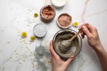 Woman preparing cosmetic clay on light background | Image Credit: © Pixel-Shot - stock.adobe.com